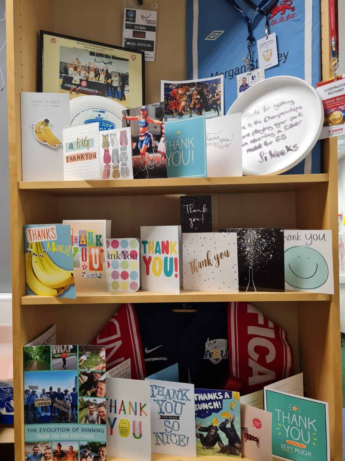 Shelves at FAST displaying handwritten thank-you cards, sporting kit, passes and memorabilia